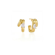 A pair of gold huggie hoop earrings with a small pear-cut clear gemstone at the center of each earring, shown on a clean white background with a soft reflection.