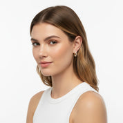 A woman with light brown hair wearing a delicate gold hoop earring, shown from the chest up against a clean white background.