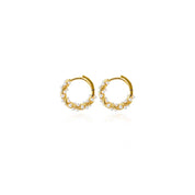 A pair of gold huggie hoop earrings decorated with small white pearls, shown on a clean white background with a subtle reflection.