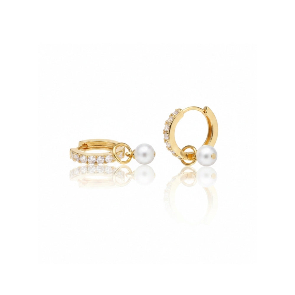 A pair of gold huggie hoop earrings, one adorned with a row of clear pavé stones and the other with a single white pearl dangling from a small gold loop, set against a clean white background with a soft reflection.