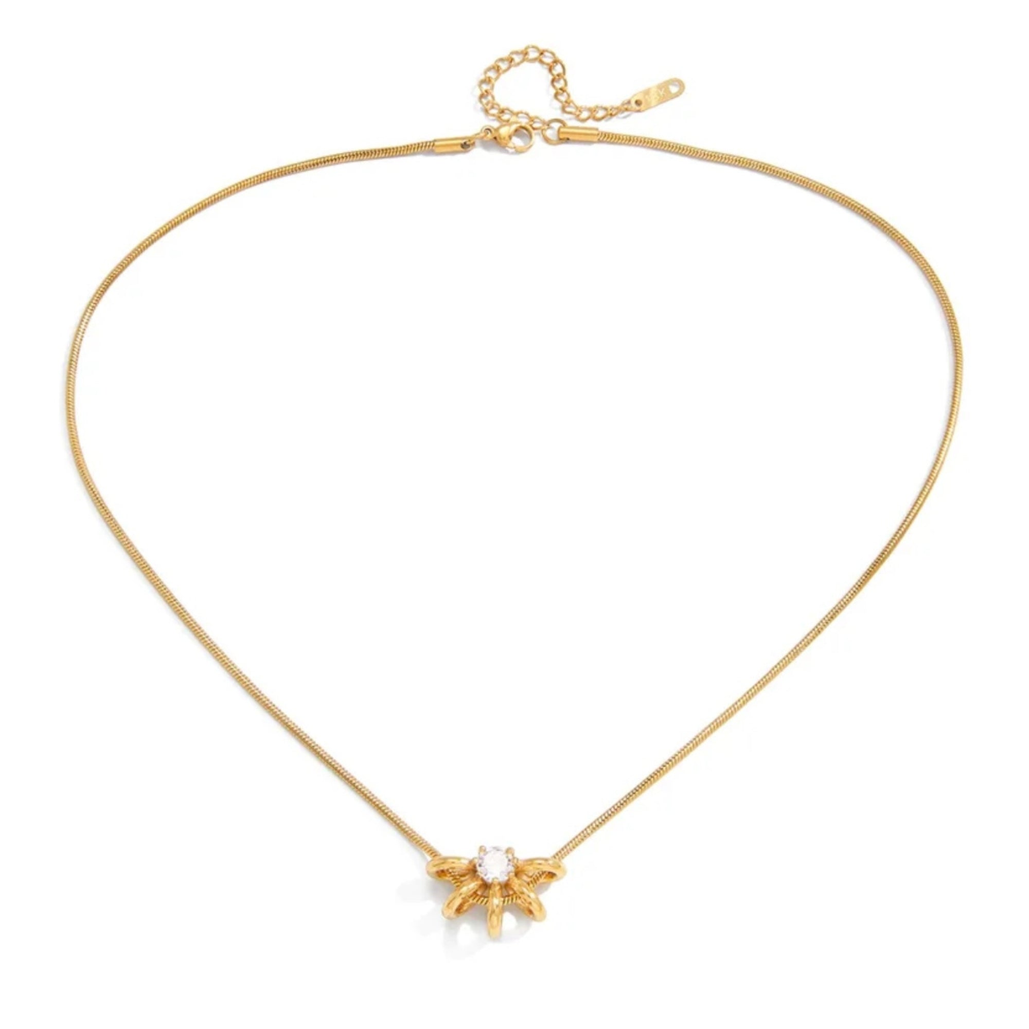 A delicate gold snake chain necklace with a small gold flower pendant featuring a clear central stone, displayed on a clean white background.