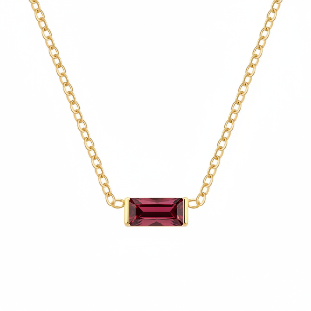 A gold chain necklace featuring a rectangular emerald-cut dark red gemstone pendant, shown against a plain white background.