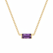 A delicate gold chain necklace featuring a rectangular emerald-cut purple gemstone pendant, displayed against a solid white background.