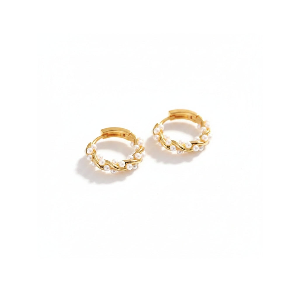 A pair of gold huggie hoop earrings adorned with small white pearls, displayed on a clean white background.