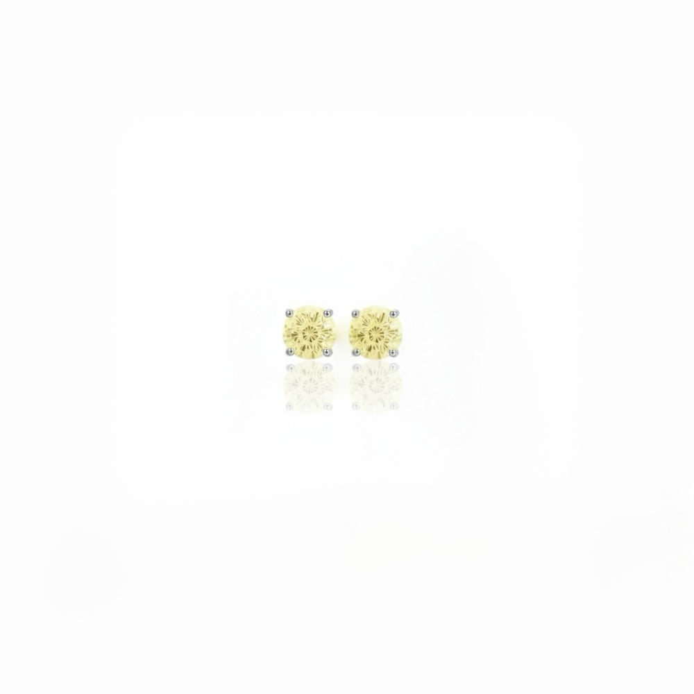 A pair of silver stud earrings with round-cut yellow gemstones, displayed on a clean white background with a soft reflection below.