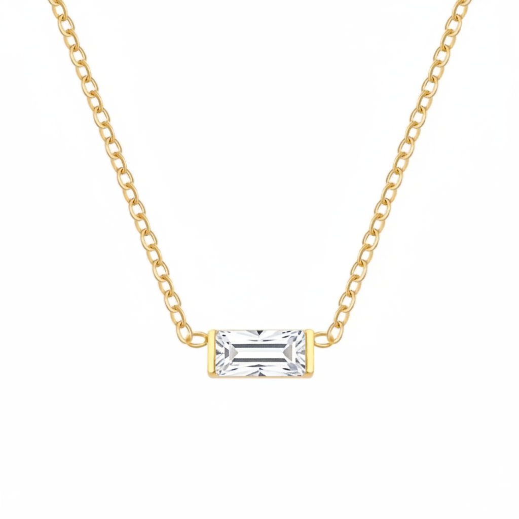 A delicate gold chain necklace featuring a rectangular baguette-cut clear gemstone pendant in a yellow gold bezel setting, shown against a plain white background.