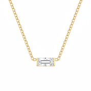 A delicate gold chain necklace featuring a rectangular baguette-cut clear gemstone pendant in a yellow gold bezel setting, shown against a plain white background.
