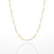 A delicate necklace featuring a twisted gold center with small white pearl-like beads draped along the sides, displayed on a clean white background with a soft reflection below.