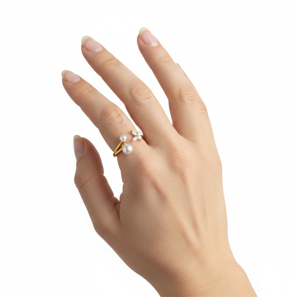 A gold ring with three small white pearls, worn on the ring finger of a hand against a plain white background.