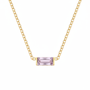 A delicate gold chain necklace featuring a small rectangular emerald-cut light purple gemstone pendant, displayed against a solid white background.