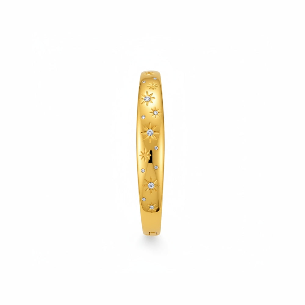 A slim yellow gold bangle bracelet featuring a row of small starburst motifs set with clear stones, shown against a plain white background.
