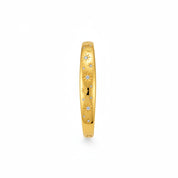 A slim yellow gold bangle bracelet featuring a row of small starburst motifs set with clear stones, shown against a plain white background.