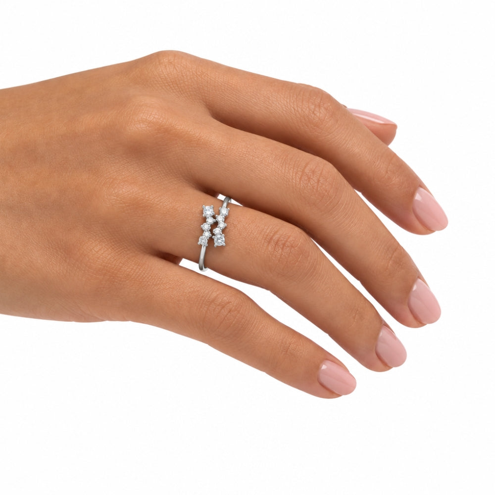 A silver ring with three small clear gemstones set in a row, shown worn on a woman's ring finger against a plain white background.