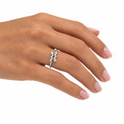 A silver ring with three small clear gemstones set in a row, shown worn on a woman's ring finger against a plain white background.