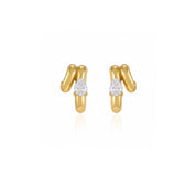 A pair of gold huggie hoop earrings with a small pear-cut clear gemstone in the center of each earring, set against a plain white background with a soft reflection below.