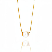 A delicate gold chain necklace featuring a single white freshwater pearl pendant, shown against a clean white background with a soft reflection below.