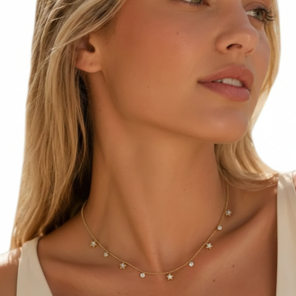 A close-up lifestyle shot of a woman wearing a delicate gold necklace adorned with small star and round bead charms.