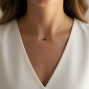 Woman wearing gold chain necklace with emerald green crystal 