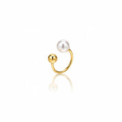 A gold open hoop ring featuring a white freshwater pearl and a polished gold bead, displayed on a clean white background with a soft reflection below.