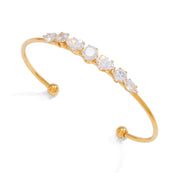 A gold open cuff bangle bracelet featuring a row of clear marquise-cut gemstones, displayed on a clean white background.