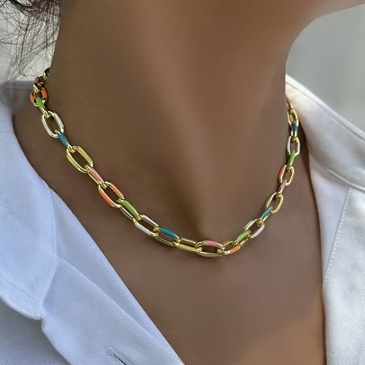 Colorful chain necklace worn by a person against a white background
