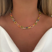 Multicolored chain necklace on a person wearing a white top
