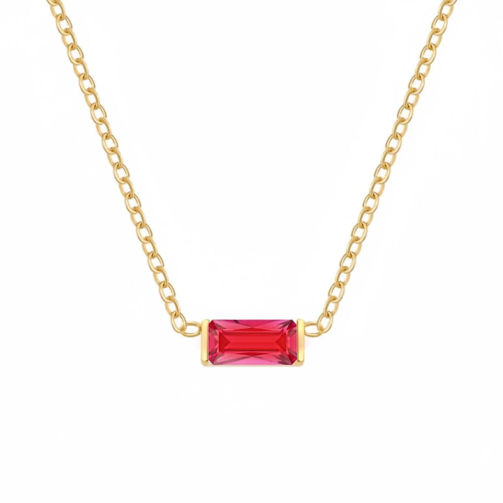 A gold chain necklace featuring a rectangular baguette-cut red gemstone pendant, shown against a plain white background.
