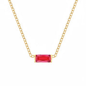 A gold chain necklace featuring a rectangular baguette-cut red gemstone pendant, shown against a plain white background.