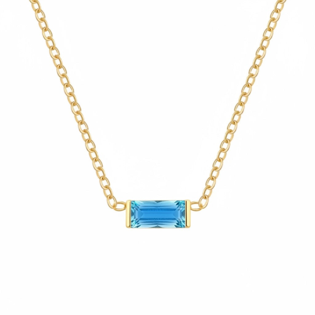 A delicate gold chain necklace featuring a small rectangular blue gemstone pendant with gold bezel settings, shown against a plain white background.