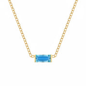 A delicate gold chain necklace featuring a small rectangular blue gemstone pendant with gold bezel settings, shown against a plain white background.
