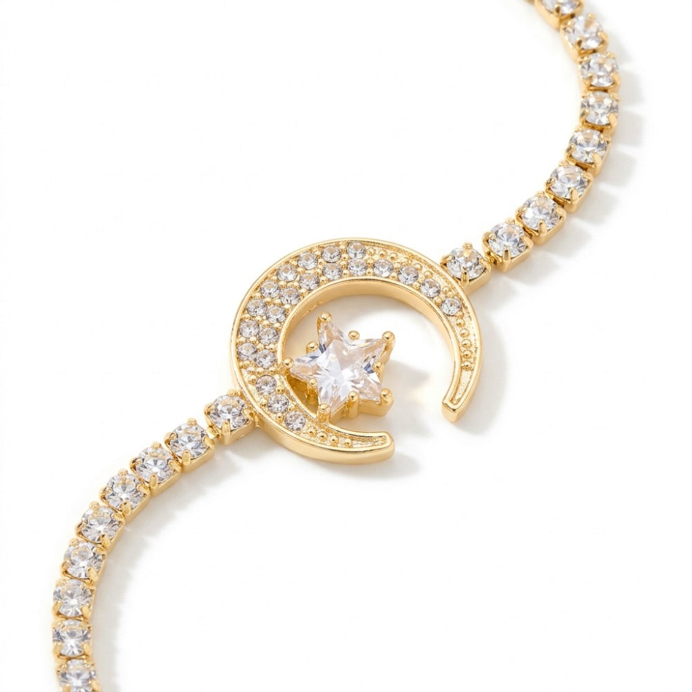 A delicate gold-toned bracelet with a crescent moon and star motif, adorned with small clear stones, shown against a white background 