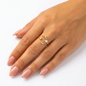 A gold crescent moon and star ring with small clear stones, shown worn on a hand with pale pink manicured nails against a clean white background.