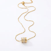 A gold chain necklace with a cylindrical pendant featuring three horizontal rows of small clear stones, displayed on a clean white background.