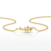A delicate gold chain bracelet featuring three star-shaped charms, each adorned with small clear gemstones, displayed on a clean white background with a soft reflection.