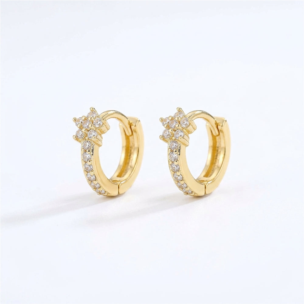 A pair of gold huggie hoop earrings with a star-shaped cluster of clear pavé stones on the front, set against a clean white background.