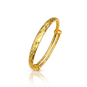 A polished gold hinged bangle bracelet with a textured, star firework-patterned outer surface, shown on a clean white background with a soft reflection below.