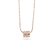 A delicate rose gold chain necklace featuring a central pendant composed of three stacked horizontal bands, with the middle band adorned with small clear stones, set against a plain white background.
