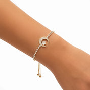 A delicate gold-toned bracelet with a crescent moon and star motif, adorned with small clear stones, shown worn on a person's wrist against a plain white background.