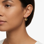 Model wearing a dainty gold huggie earrings with dangling star and crescent moon charms 