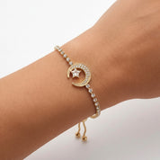 A gold crescent moon and star charm bracelet with clear rhinestone accents, shown worn on a person's wrist against a clean white background.