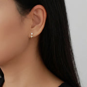 Close up of a dainty gold sparkling star earring worn on the earlobe 