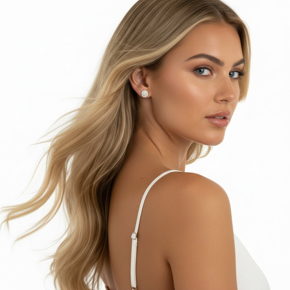A blonde woman with long wavy hair is shown in profile against a clean white background, wearing a small round stud earring. She is wearing a white spaghetti-strap top.