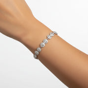 A silver-toned diamond bracelet with round pavé-set floral motifs, shown worn on a person's wrist against a clean white background.