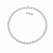 A silver tennis bracelet featuring round pavé-set clear stones, displayed on a clean white background with its clasp and extender visible.