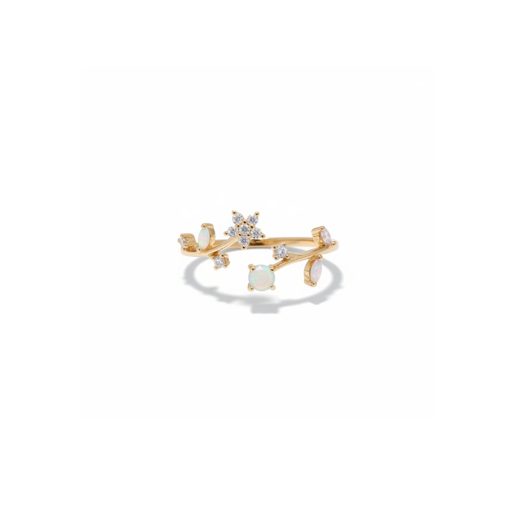 A gold ring featuring a central round white opal surrounded by small clear stones, with additional white opal stones set along curved gold branches, shown on a clean white background.