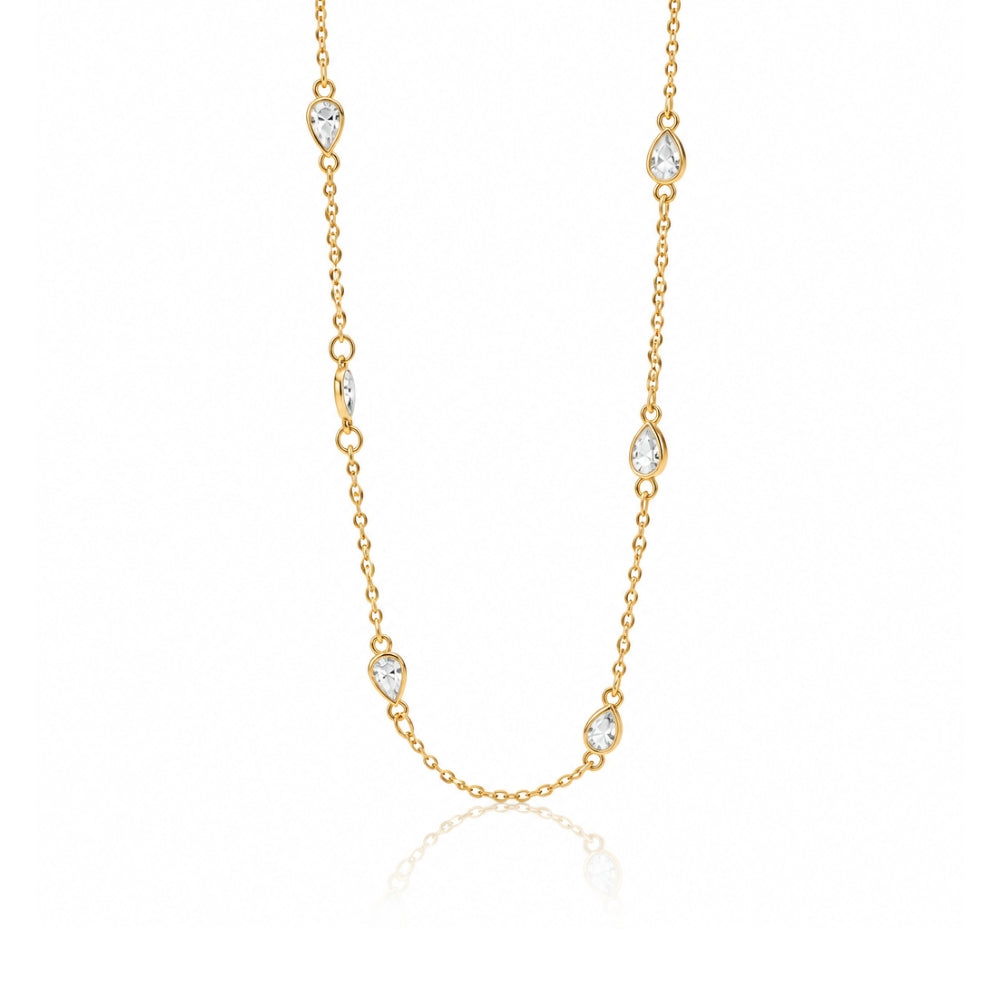 A delicate gold chain necklace featuring seven small pear-cut clear gemstones spaced along the chain, displayed on a clean white background with a soft reflection below.
