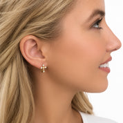 Side profile view of a model wearing a gold cz cross huggie earring 