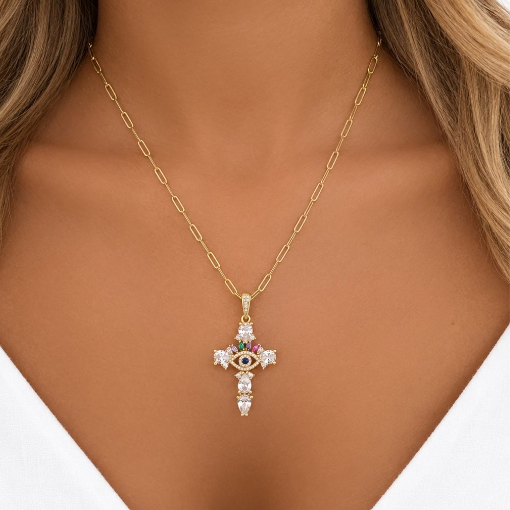 Close-up of a model wearing the gold-tone evil eye cross necklace on a paperclip chain with a white V-neck top.