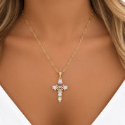 Close-up of a model wearing the gold-tone evil eye cross necklace on a paperclip chain with a white V-neck top.