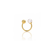A gold U-shaped ring with a polished gold ball on one end and a white freshwater pearl on the other, displayed on a clean white background with a soft reflection below.